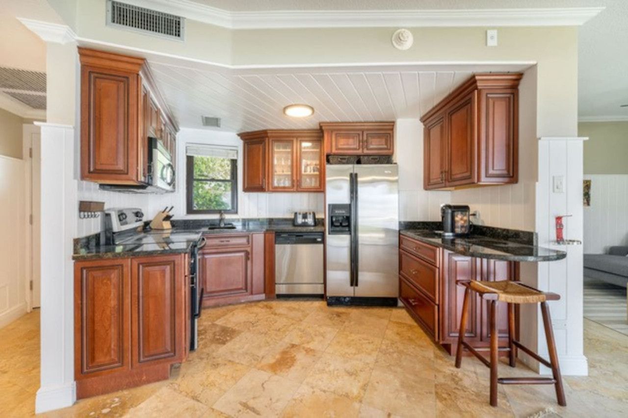 Una cocina con armarios de madera, un refrigerador de acero inoxidable y una encimera de granito.