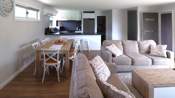 Un espacio de estar moderno con comedor, un conjunto de sofás y una cocina al fondo.