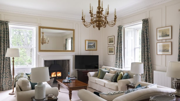A classic living room with a fireplace, comfortable seating, and a large mirror.