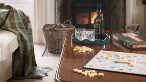 A cozy living room with a fireplace, a table with Scrabble tiles, a bottle, and a Scrabble box.