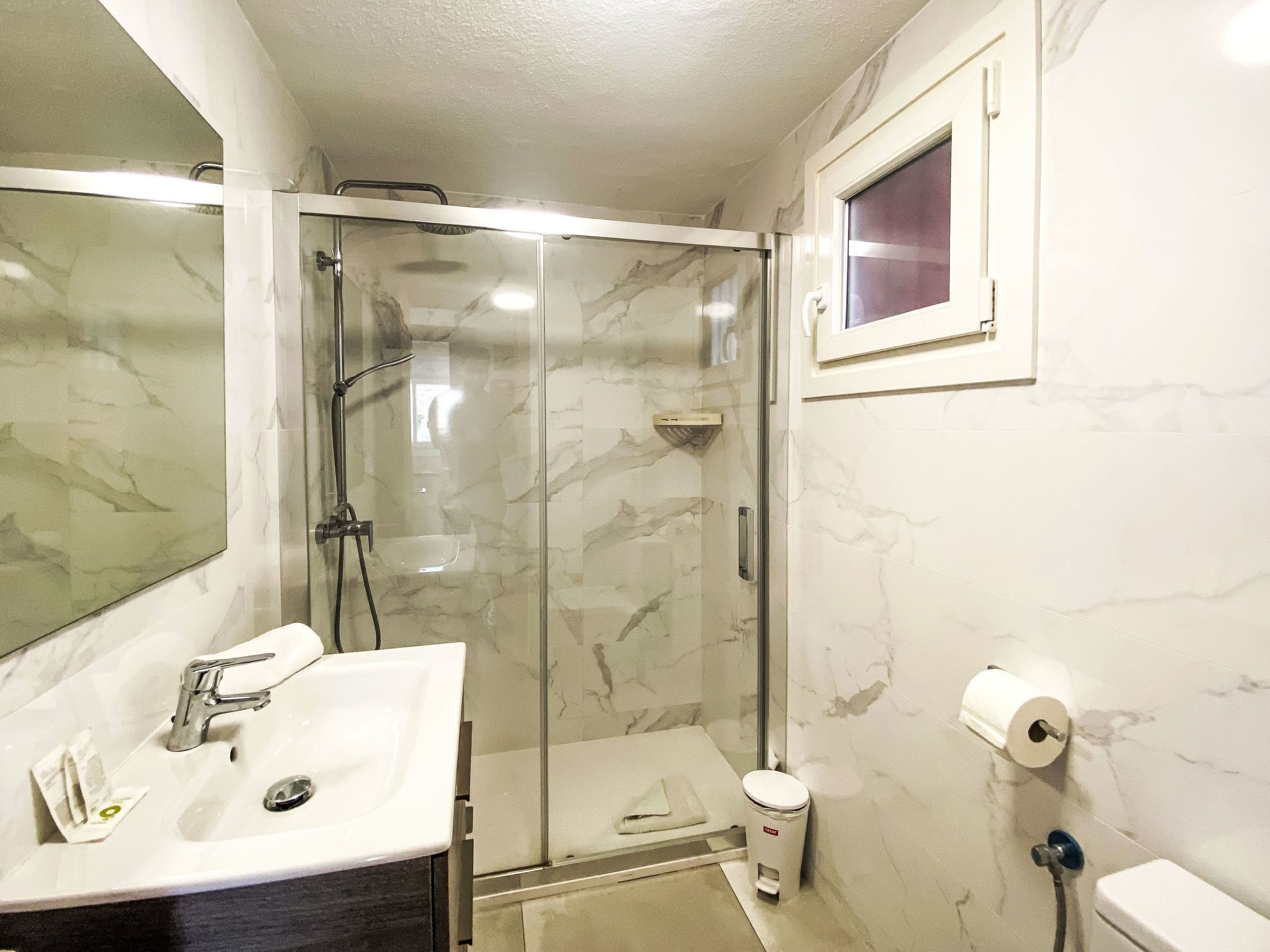 Une salle de bain avec une douche à parois de verre, un lavabo avec un miroir et des toilettes.
