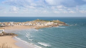 Une ville côtière avec une plage, des bâtiments et un fort situé sur une colline.
