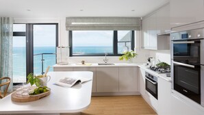 Une cuisine moderne dotée d’un grand îlot central, offrant une vue sur l’océan et comprenant un four encastré.