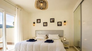 A bedroom with a large bed, two bedside tables, a chandelier, and framed pictures on the wall. - Villa Passera by Interhome (Dénia)