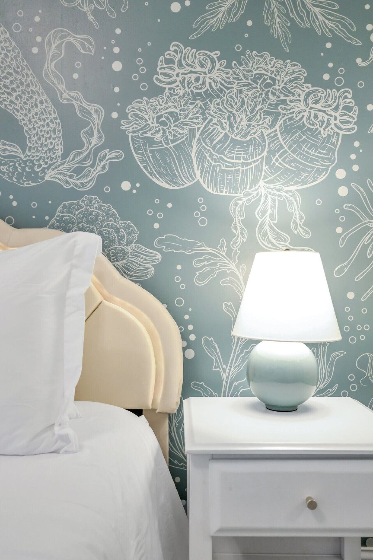 A bedroom with a bed, a nightstand, and a wall with a decorative pattern.