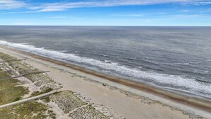 A coastal road with a beach on one side and a clear sky. - Salt & Sea Inn Unit A-1 Bed 1 Ba Condo w/Pool (Tybee Island)