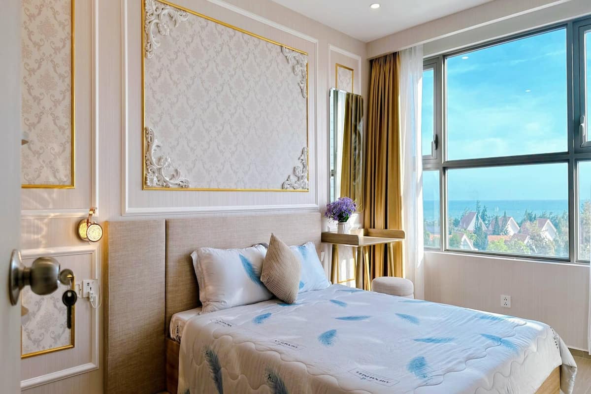 A hotel room with a large bed, a view of the city, and a window with curtains.