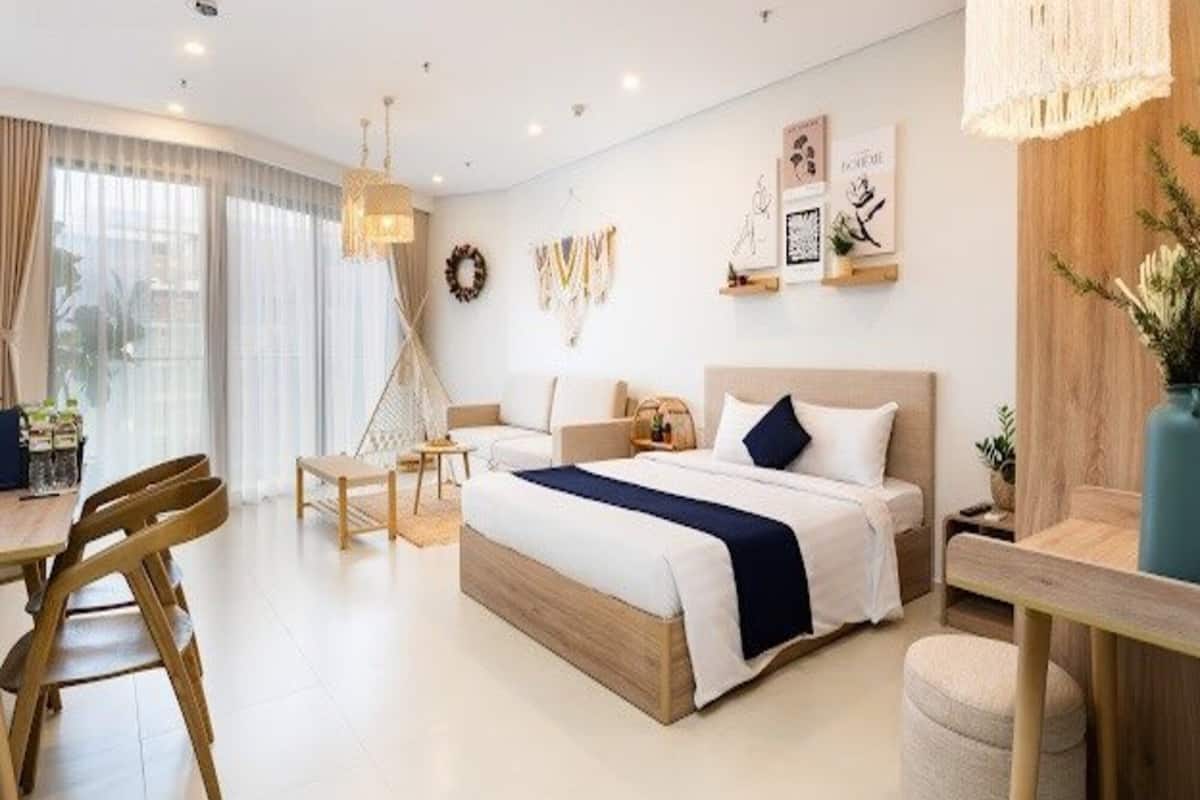 A modern hotel room with a large bed, a desk, and a dining area.