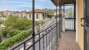 Un balcon doté d’une rambarde en métal, donnant sur une rue bordée d’immeubles et d’espaces verts.