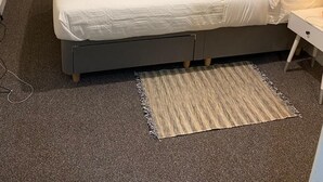 A bedroom with a bed, bedside table, radiator, and a window with a dark blind. - Stunning 2-Bed Apartment in London (London)