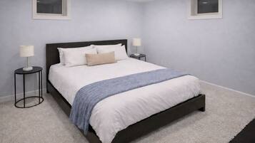 Une chambre avec un lit en bois foncé, du linge de lit blanc, un plaid bleu, deux lampes de chevet et un tapis blanc.