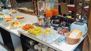 Un buffet con diversi cibi, tra cui frutta, dolci e bevande.