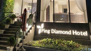 L'ingresso di un hotel con una scalinata che conduce all'ingresso, un cartello con la scritta 'Ping Diamond Hotel' e una vista dell'interno attraverso le finestre.