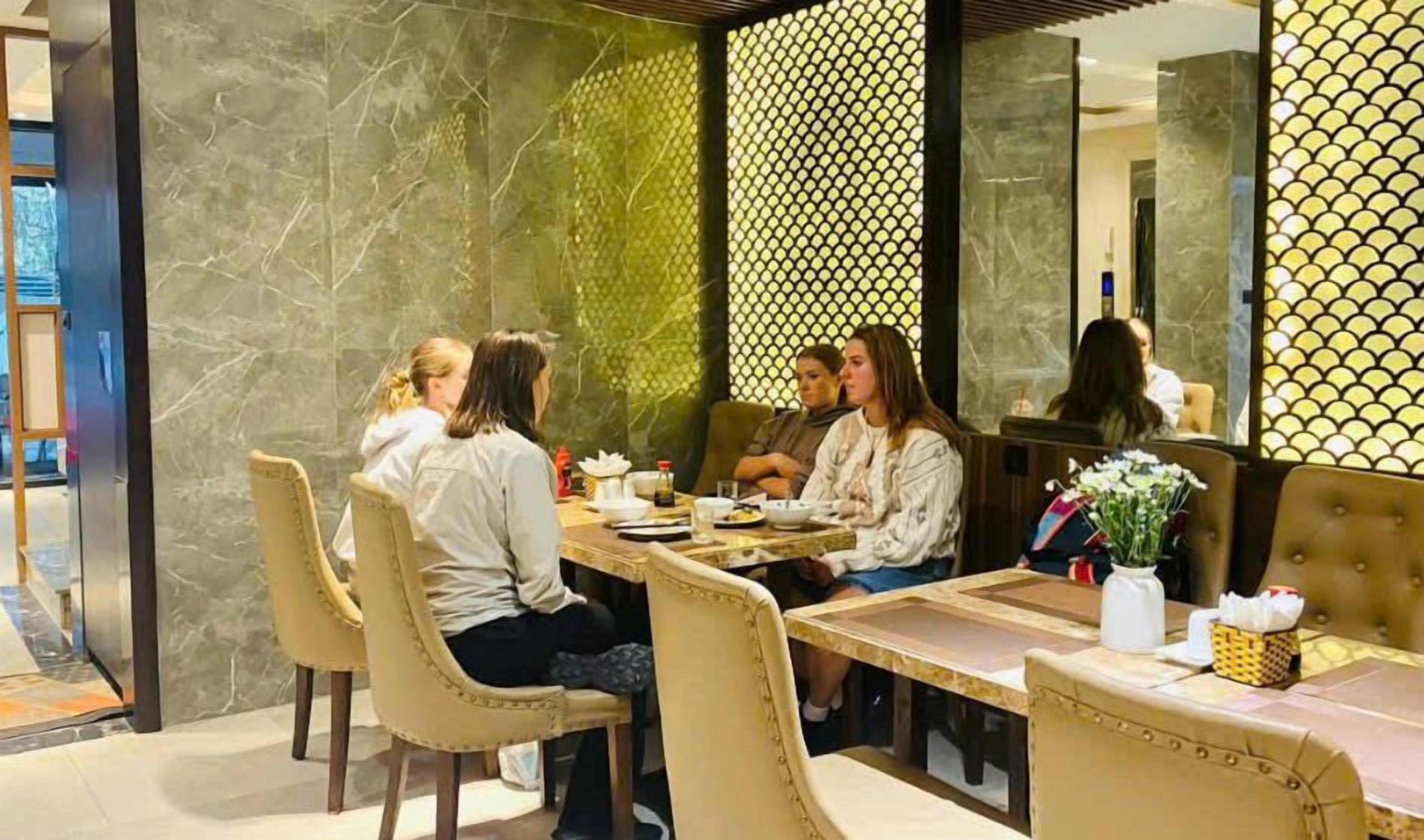 Un comedor con pared de mármol, separador decorado y un espejo que refleja la estancia.