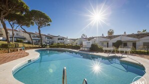A swimming pool with a curved edge, surrounded by a paved area and trees. - Nico | Sea Siew - Pool - Beach (Sitio de Calahonda)