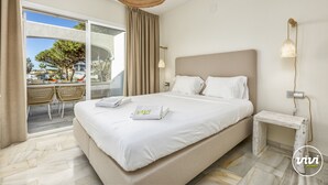 A bedroom with a large bed, a small bedside table, a hanging light, and a view of the outdoors. - Nico | Sea Siew - Pool - Beach (Sitio de Calahonda)