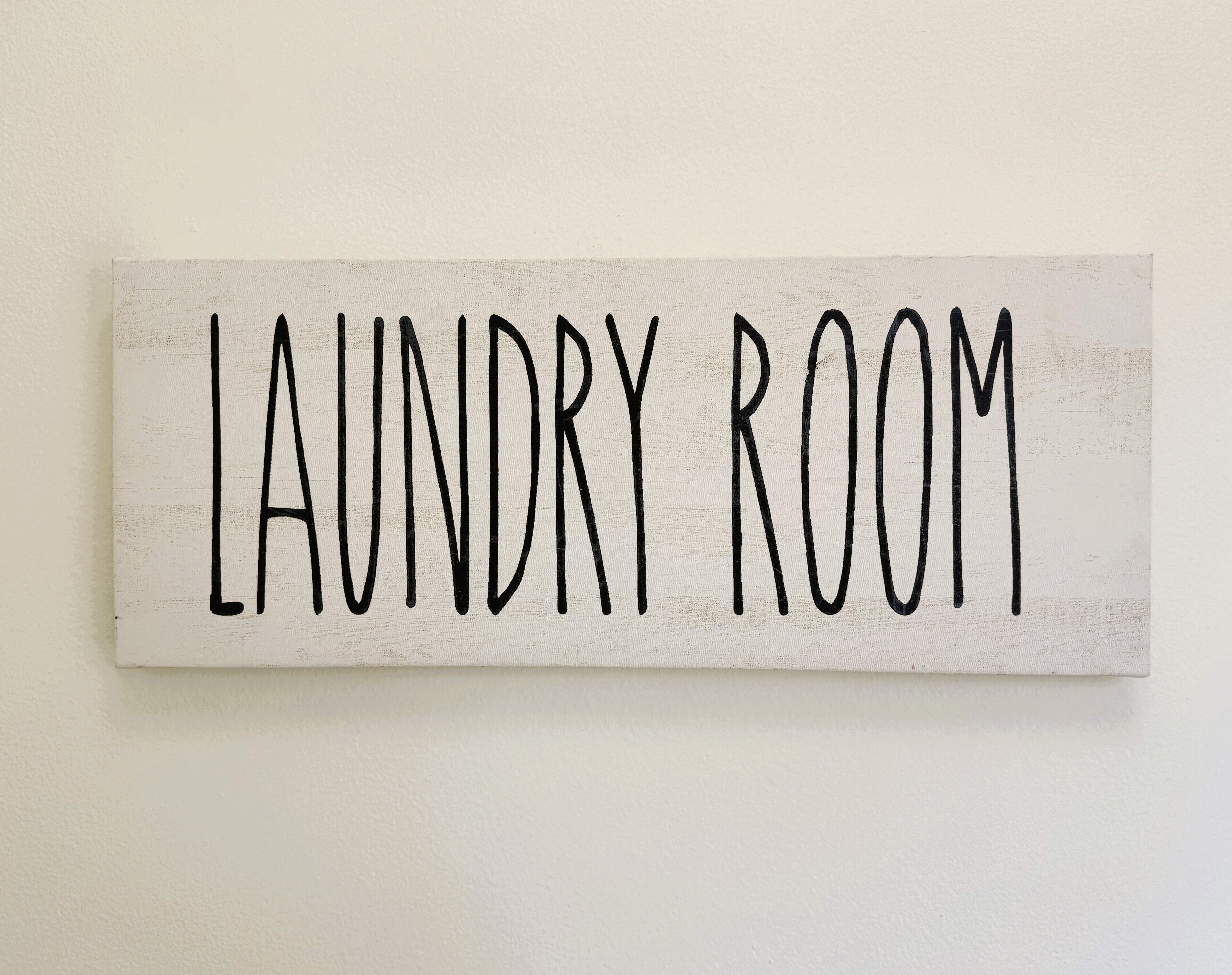 Ein Schild mit der Aufschrift 'LAUNDRY ROOM' vor weißem Hintergrund.