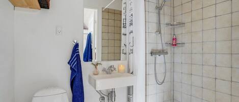 Een badkamer met een witte wastafel, spiegel en douche.