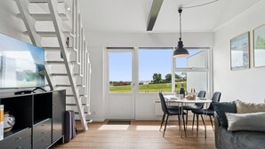 Una sala de estar moderna con televisor, comedor y escalera.