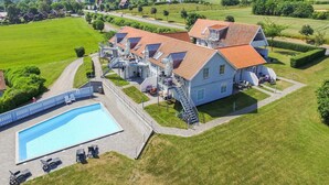 Un grande hotel con diversi edifici, una piscina e un prato curato.