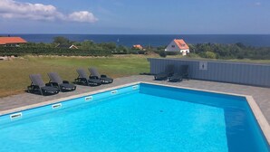 Una piscina rettangolare con acqua cristallina e lettini da relax intorno.