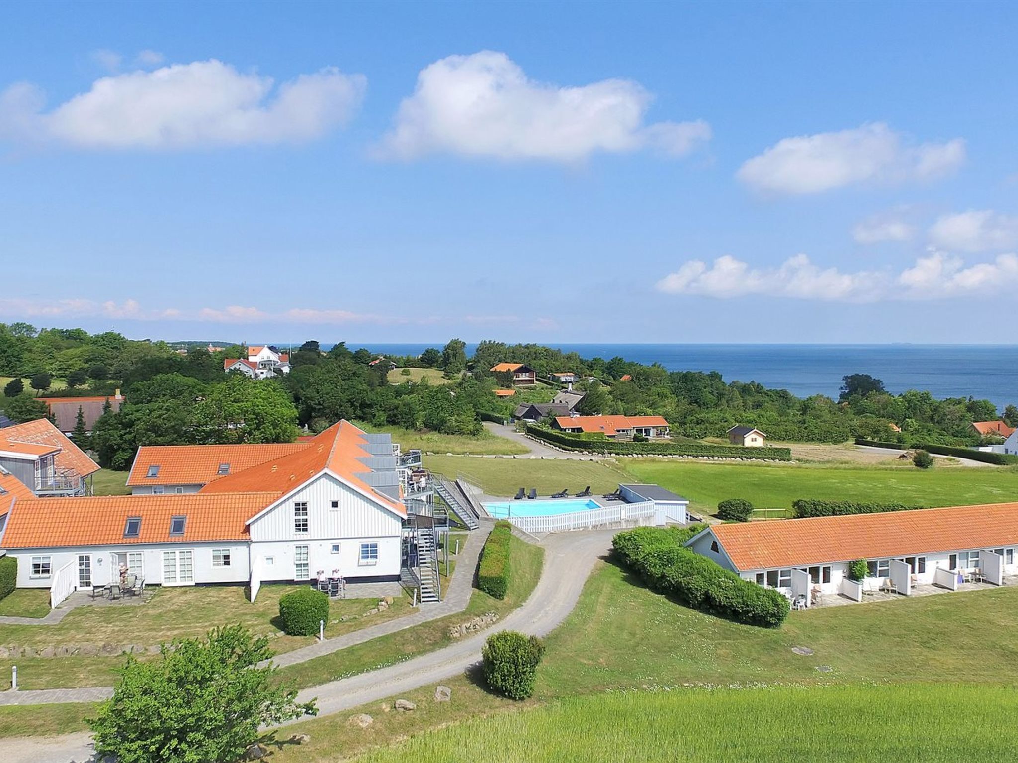 A coastal property with a large white building, a swimming pool, and a view of the sea.