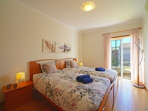 A double bed with floral bedding, a nightstand with a lamp, and a painting above the bed. - Sunny Beach Diamond by Interhome (Armação de Pêra)