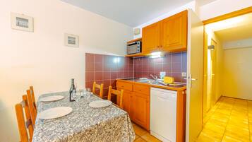 A compact kitchen with wooden cabinets, a built-in microwave, and a dishwasher.