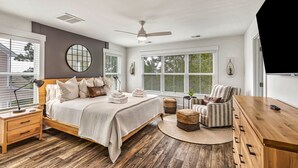 A bedroom with a bed, nightstand, chair, and a TV. - Beach, Private Pool, Designer Everything, Exclusive  Community (Hilton Head Island)