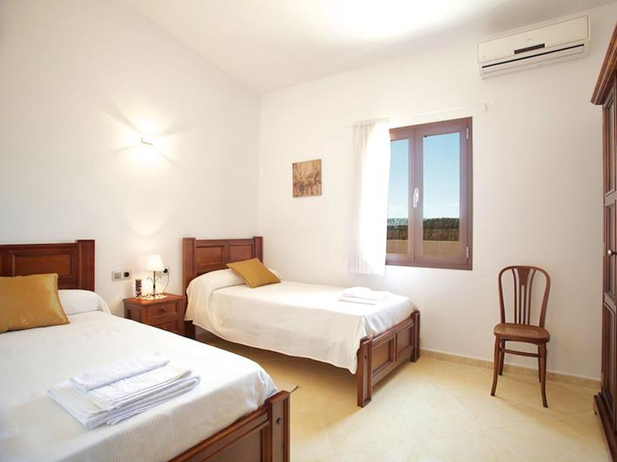 Ein Hotelzimmer mit zwei Betten, einem Sessel, einer Klimaanlage und einem Fenster mit Blick.