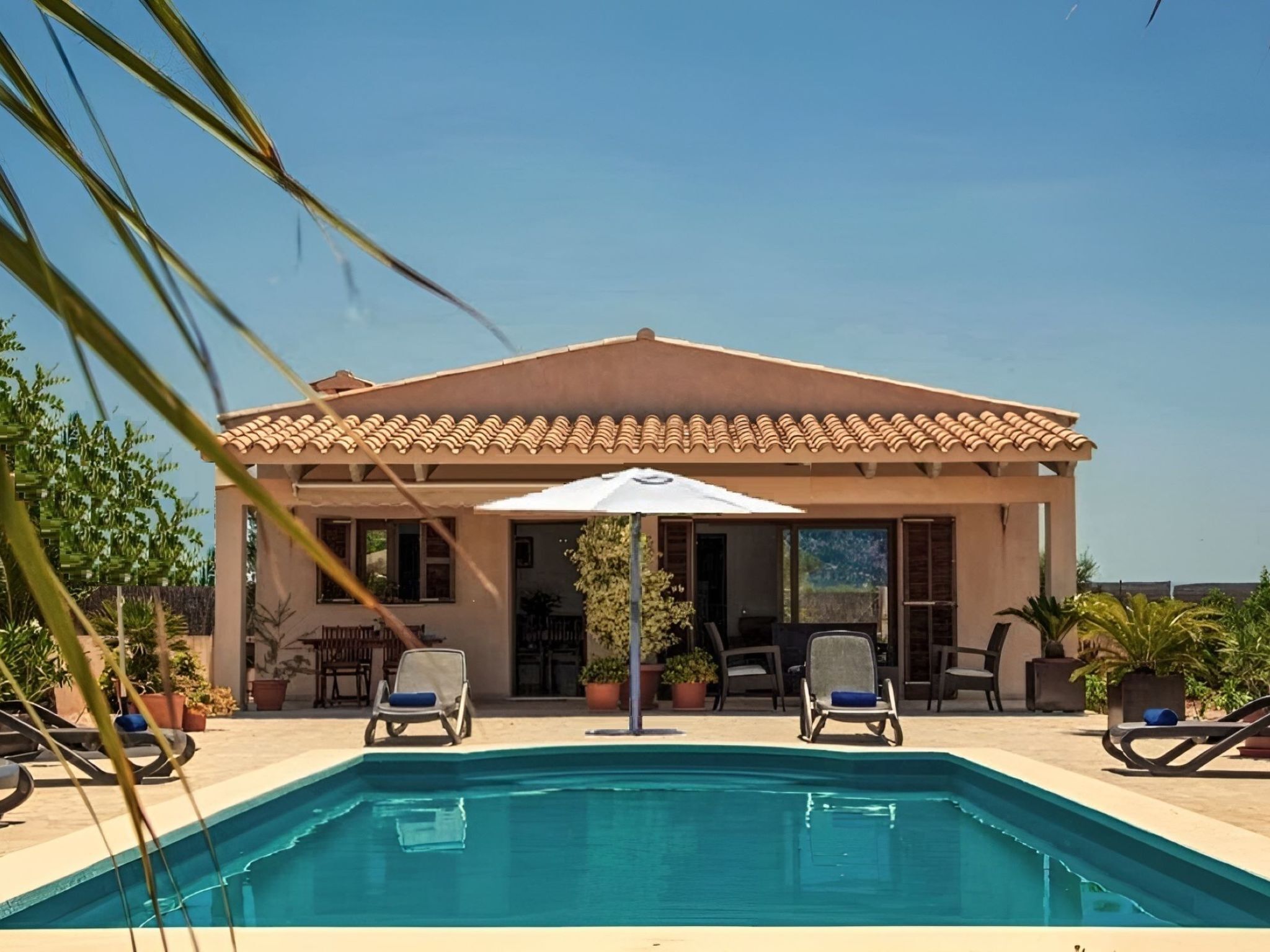 Un espace aménagé au bord de la piscine, comprenant une piscine, des chaises longues et un patio couvert.