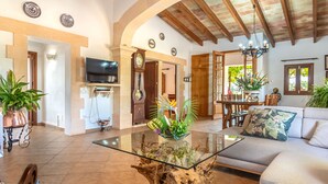 A spacious living room with a glass coffee table, a sofa, and a dining area with a wooden table and chairs.