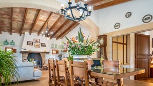 A spacious living room with a wooden dining table, chairs, and a chandelier.