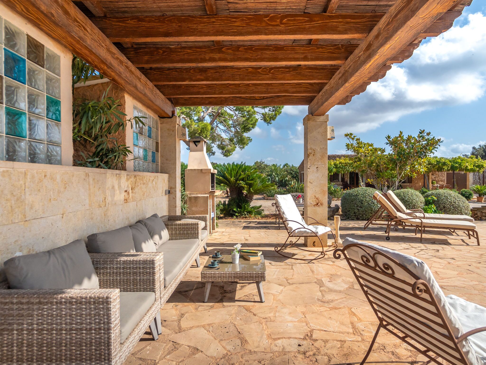 Un espace extérieur aménagé en terrasse, avec des meubles en osier, un sol en pierre et une structure en forme de pergola.