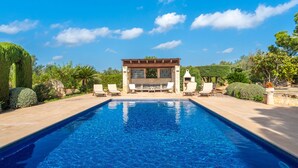 A swimming pool with lounge chairs and a barbecue area, surrounded by landscaped greenery.