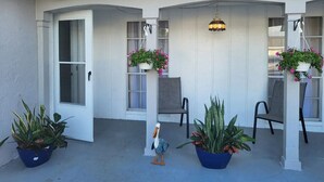 An outdoor patio area with white walls, a hanging light fixture, and several potted plants. - Beautiful pool house in Holiday, Florida.  (Holiday)