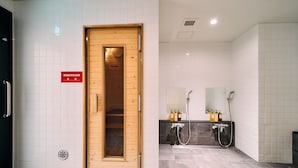 Un baño moderno con sauna, un lavamanos con espejo y paredes con azulejos.