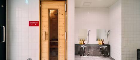A modern bathroom with a sauna, a sink with a mirror, and tiled walls.