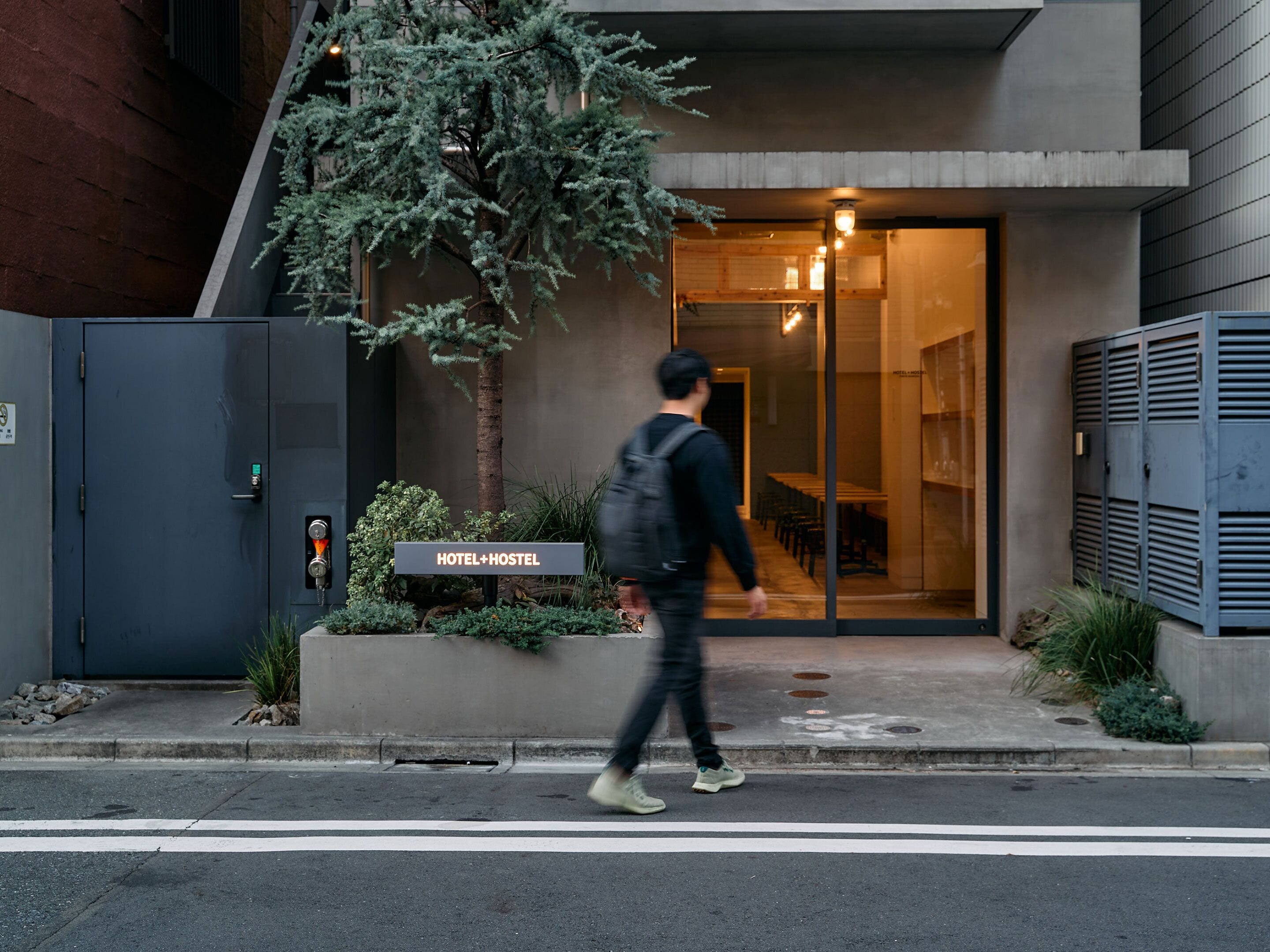 A hotel entrance with a sign reading "HOTEL+HOSTEL".