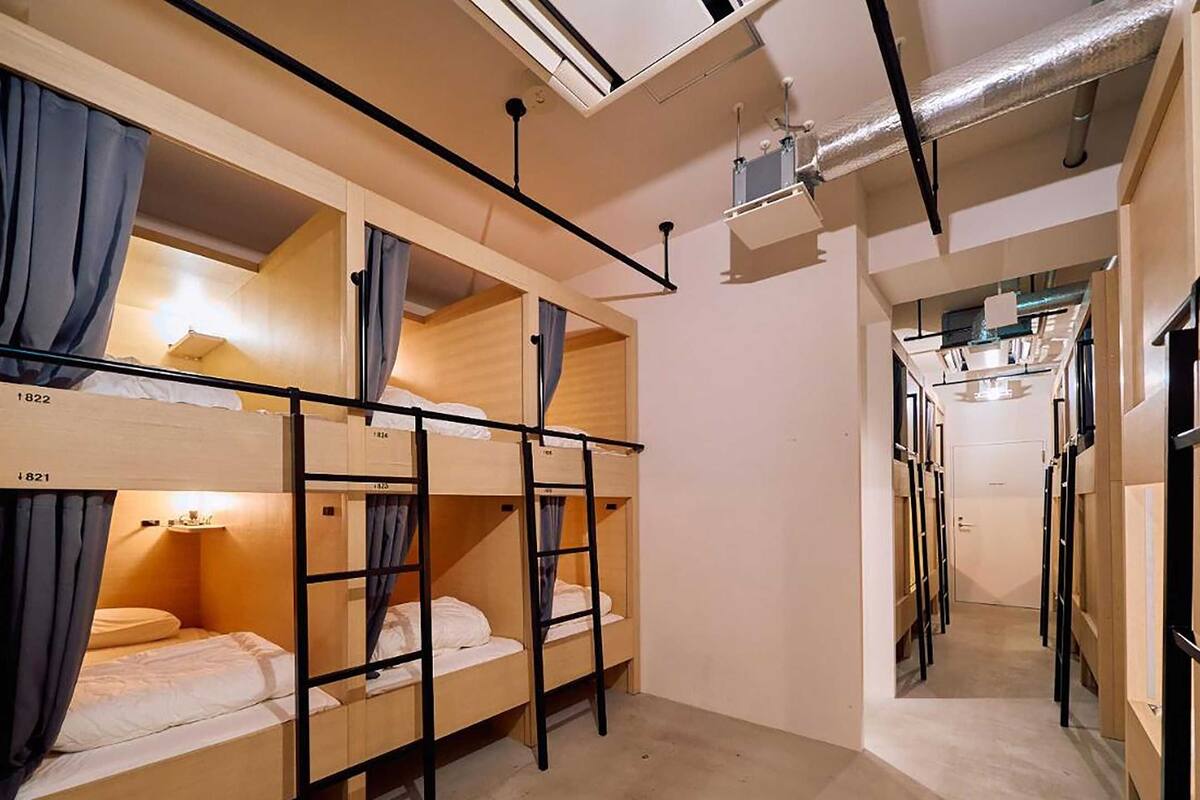 Una camera del dormitorio con letti a castello, una scala e una piccola scrivania con una lampada.