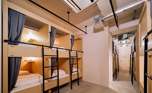 Une chambre de dortoir avec des lits superposés, une échelle et un petit bureau avec une lampe.