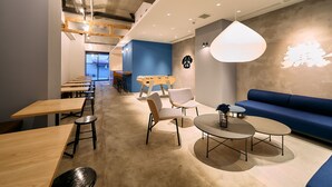 Un interior moderno con una larga zona de comedor, una mesa de fútbol y un sofá azul.