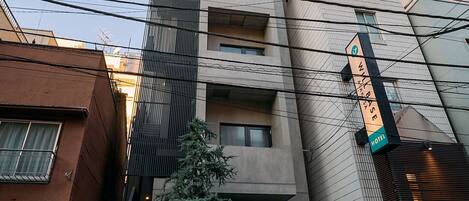 Ένα ξενοδοχείο με μια μοντέρνα πρόσοψη, μια ευδιάκριτη είσοδο και μια πινακίδα που υποδεικνύει ότι πρόκειται για ένα ξενοδοχείο που λειτουργεί ως βάση.