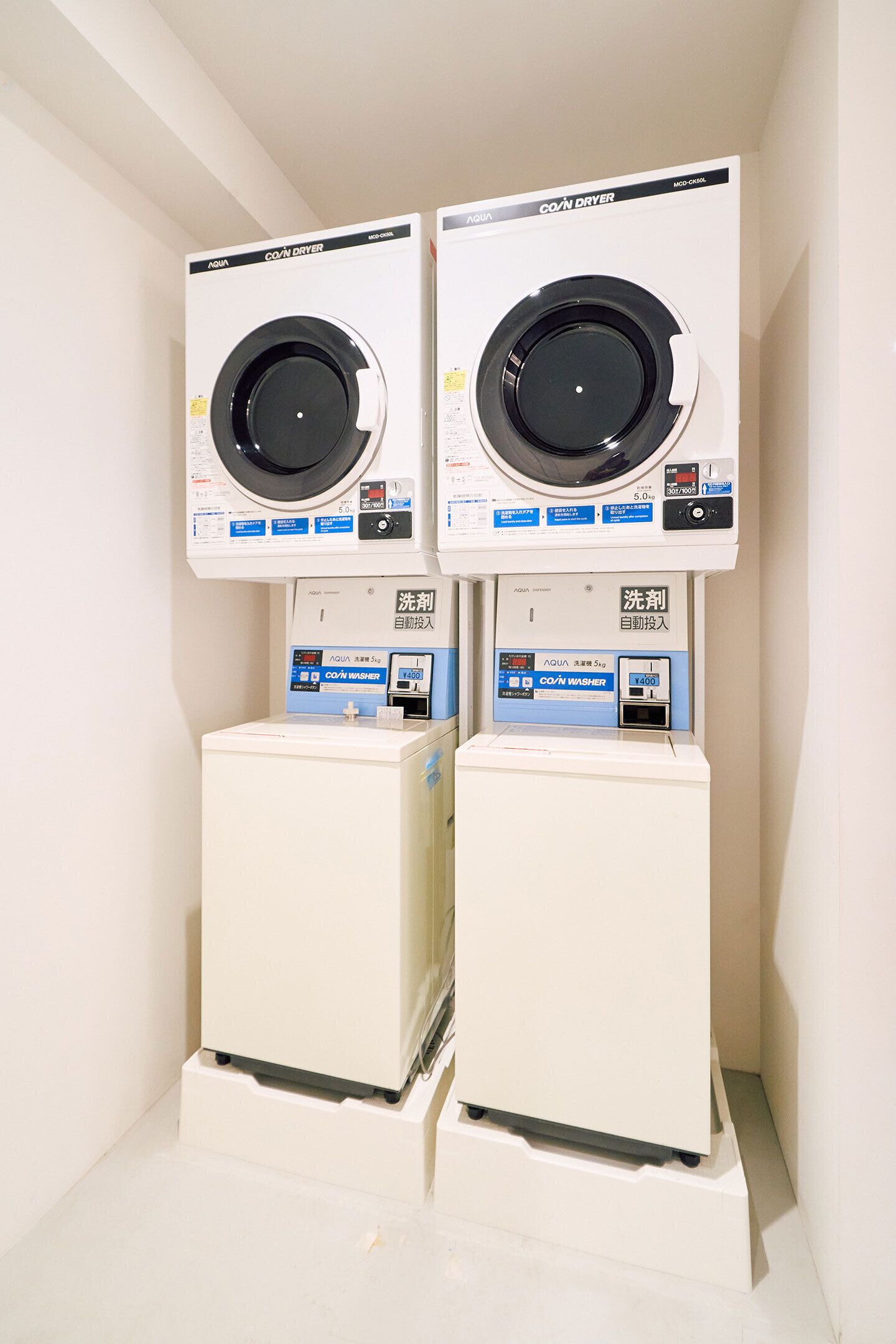 Two stacked washing machines with control panels and a detergent dispenser.