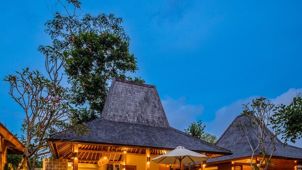 A poolside area with a clear pool, lounge chairs, and thatched-roof structures. - Kaju Bungalow by Betterplace (Canggu)