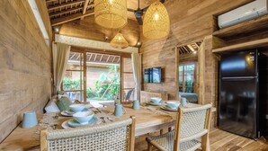 A wooden interior with a dining table set for four, surrounded by wicker chairs. - Kaju Bungalow by Betterplace (Canggu)