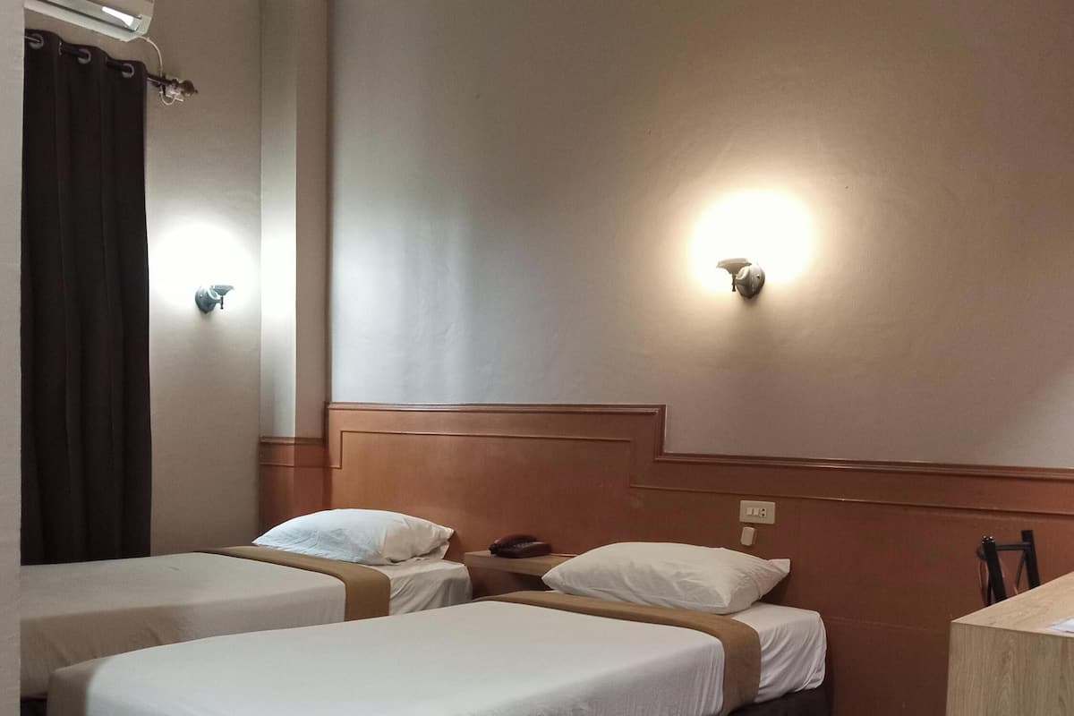 Une chambre d’hôtel avec deux lits, une tête de lit en bois, un bureau et une chaise.