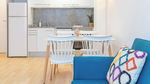 A compact kitchen with white cabinets, a granite countertop, and a dining area with a white table and chairs. - Palamós: Playa, Sol y Parking incluido (Palamos)