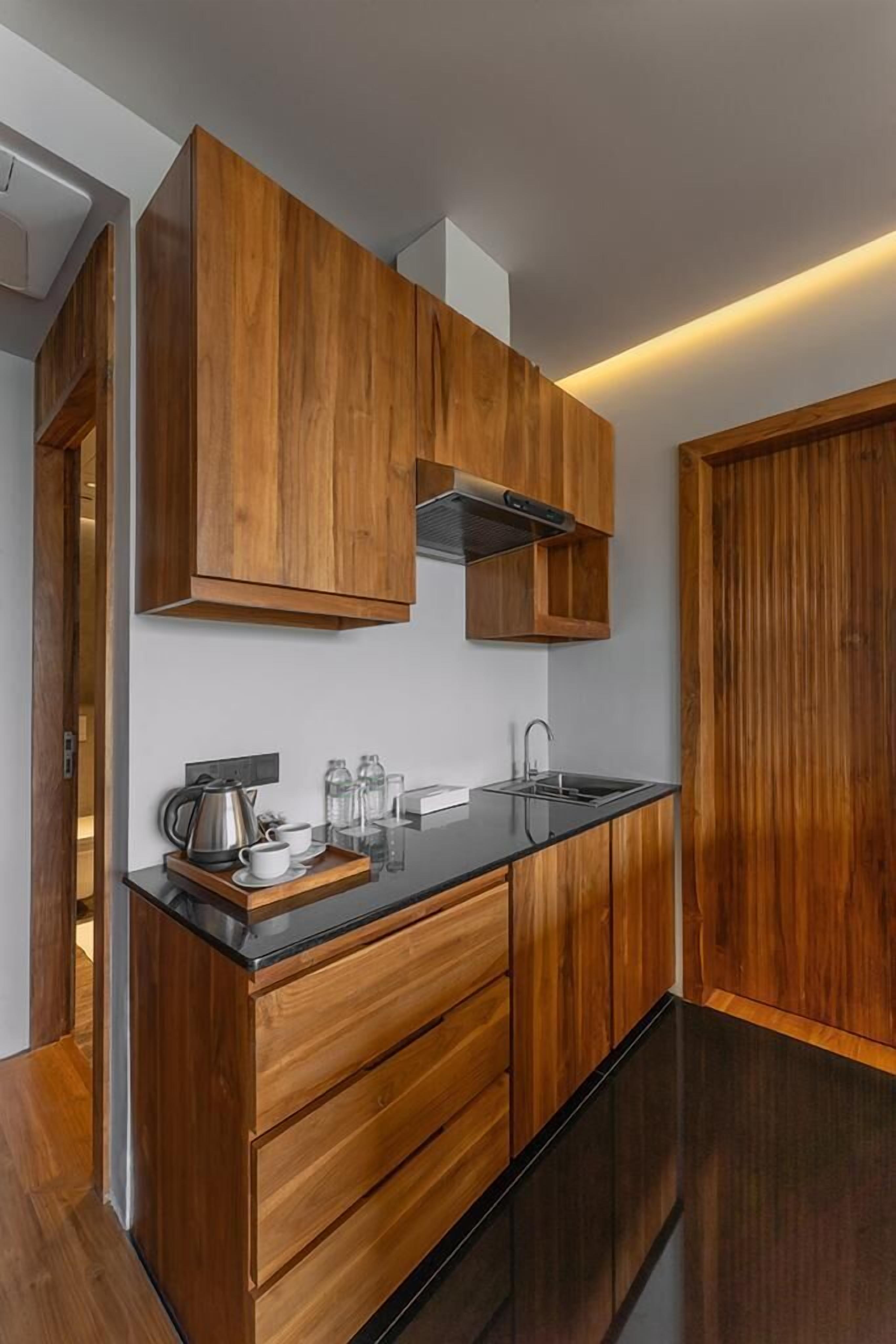 Una cocina moderna con armarios de madera, encimera negra y pileta de acero inoxidable.