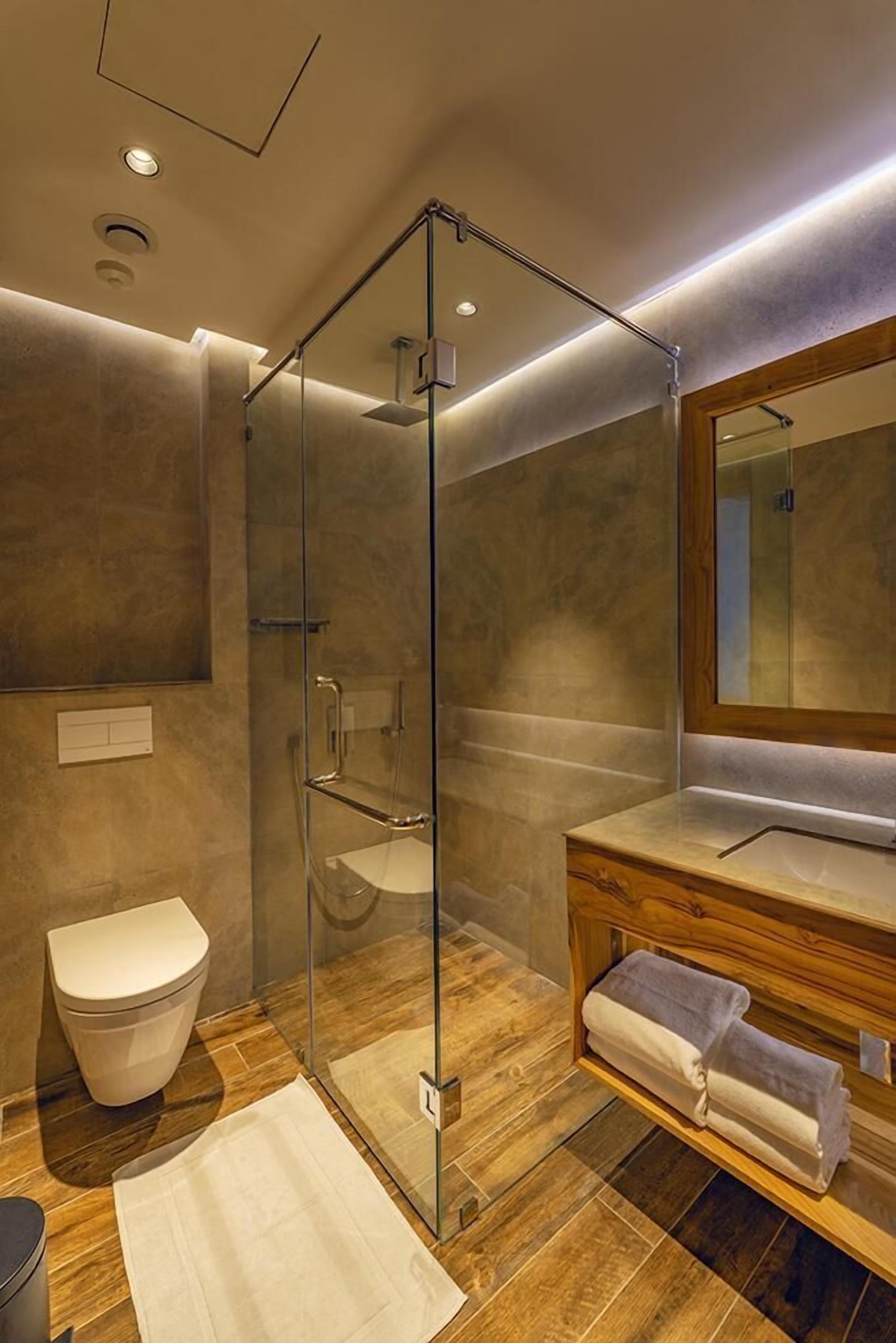 Un bagno moderno con doccia vetrata, un mobile bagno in legno e uno specchio grande.